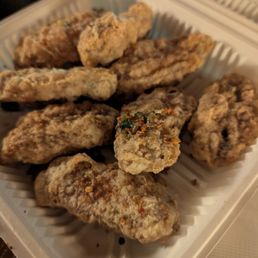 Salt & Pepper Chicken Wings - Fried chicken wings with batter coating are arranged in a plastic takeout container, some with visible seasoning and herbs.