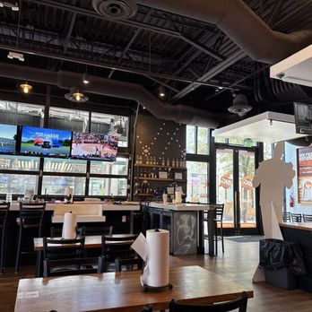 Big Chicken - Interior/bar area of Big Chicken - A restaurant interior featuring multiple mounted TVs, seating arrangements, and a large chicken cutout figure near the entrance. - Burgers Near Me - Gilbert, Arizona