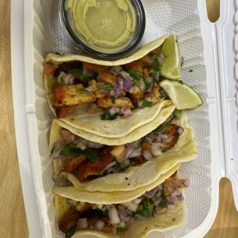 Everything Halal - 3 pc Chicken Tacos with Sauce - Four tacos filled with grilled chicken, garnished with chopped onions and cilantro, accompanied by lime wedges and a small container of green sauce. - Fast Food Near Me - Irving, Texas