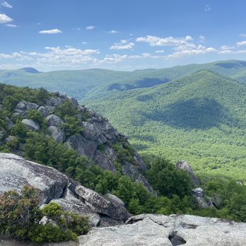 Old Rag Mountain - Scenic view of lush green mountains with rocky formations in the foreground, under a partly cloudy sky. - Hiking Near Me