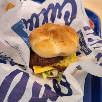 Culver's - Butter burger - A cheeseburger with a beef patty, melted cheese, lettuce, and a bun is placed on a tray with branded paper wrapping. - Burgers Near Me - Madison, Wisconsin