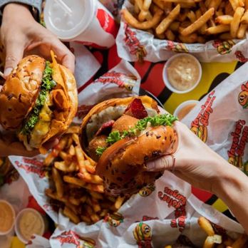 Taystee's Burgers - Close up of two people holding their burgers at Taystee's in Dearborn - Burgers Near Me - Dearborn, Michigan Taystee's Burgers - Close up of two people holding their burgers at Taystee's in Dearborn - Burgers Near Me - Dearborn, Michigan