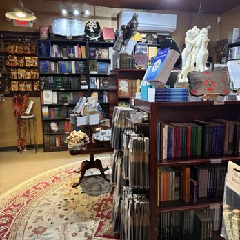 Pentagram: Witchcraft & Magick Shoppe - Interior of a bookstore or shop with bookshelves, statues, and decorative items, including a round table with books and a carpeted floor. - Spiritual Shop Near Me - Salem, Massachusetts