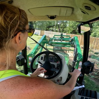 Emerald Coast Tree Services - Cockpit view of John Deere 4044R lifting large oak logs. - Tree Services Near Me - Pace, Florida