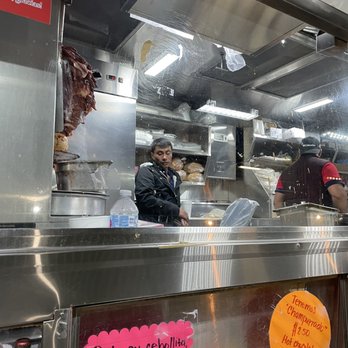Tacos Los Primos Soloma - Young man without a mask, inside of the truck with the cook. - Tacos Near Me - Los Angeles, California Tacos Los Primos Soloma - Young man without a mask, inside of the truck with the cook. - Tacos Near Me - Los Angeles, California