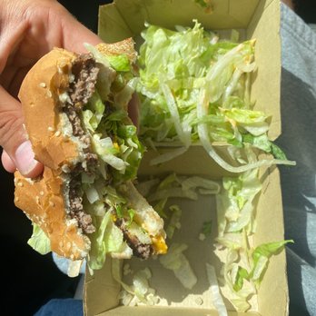 McDonald's - a hand holding a hamburger with lettuce - Fast Food Near Me - Wright, Florida
