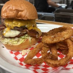 Original Breakfast House - Our beach burger topped with cheddar cheese, two strips of bacon, three house made onion rings and bbq sauce.