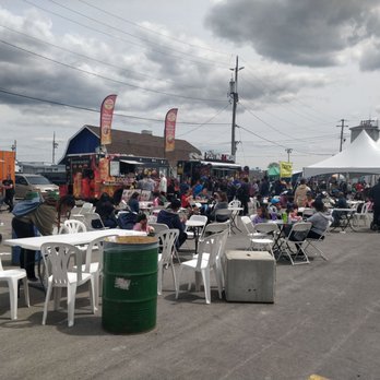 KidsFest - A busy outdoor food festival features food trucks, a large white tent, and numerous tables and chairs with people dining. - Kids Activities Near Me - Markham, Ontario