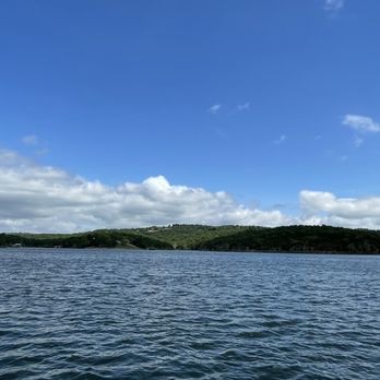 Floating Cafe - The lake view - A landscape featuring a large body of water with gentle ripples, bordered by green hills in the background. The sky above is partly cloudy with patches of blue visible. The scene captures a peaceful outdoor setting, likely near a natural or recreational area. - Cafes Near Me - Branson, Missouri