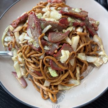 Mr Dumpling - Pork fried noodles - A bowl of pork fried noodles with cabbage, bacon, and vegetables, served in a restaurant setting. - Dim Sum Near Me - Eugene, Oregon