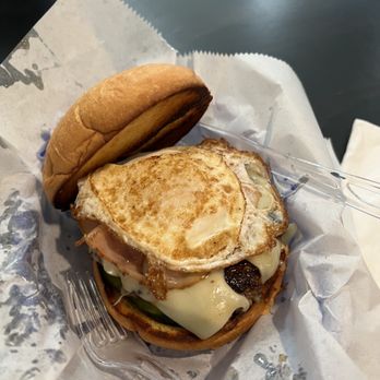The West Egg - Cuban.... A+mazing!!!! - A breakfast sandwich featuring a fried egg, melted cheese, and vegetables in a bun, served with a side of a small bread roll. - Coffee & Tea Near Me - St. Augustine, Florida