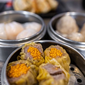 IT DIMSUM - Pork Shumai ($5) - Close-up of steamed dumplings and shumai in metal containers, with a blurred background of additional dim sum dishes. - Dim Sum Near Me - Albuquerque, New Mexico