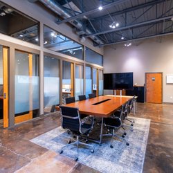 GeniusDen - A look inside Genius Den in Deep Ellum, Dallas, with shared tables and glass-front offices.