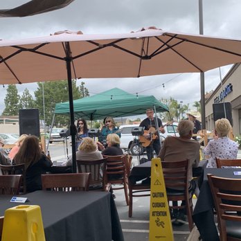 Our Place - a group of people sitting at tables under umbrellas - New American Near Me - Lake Forest, California Our Place - a group of people sitting at tables under umbrellas - New American Near Me - Lake Forest, California