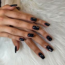 Glossy black polish with delicate white dots for a timeless, playful finish.