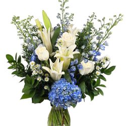 White lilies, roses, blue hydrangea, and delphinium create a serene bouquet inspired by clear skies and peaceful beauty.