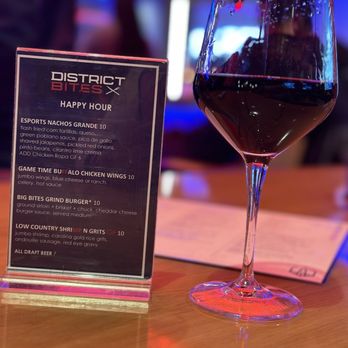 District Bites - A glass of red wine is placed on a wooden table next to a menu from District Bites, a restaurant near Capital One Arena in Washington, DC. - Desserts Near Me - Washington, DC, District of Columbia