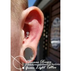 Conch piercing with a 3-stone cluster. Performed by Dianna