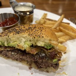 The burger with bacon cheese avocado on a sweet Hawaiian bread type sesame bun and fresh cut fries with catchup and ranch.