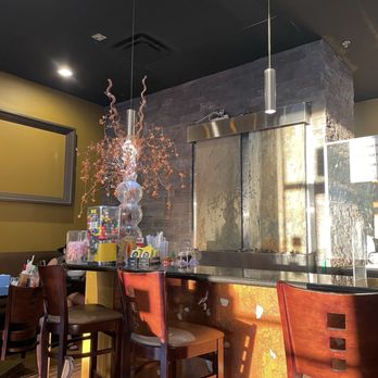 Pho Number One - A restaurant interior featuring a bar with high chairs, a decorative light fixture, and a stone wall behind the bar area. - Vietnamese Near Me - Mesa, Arizona