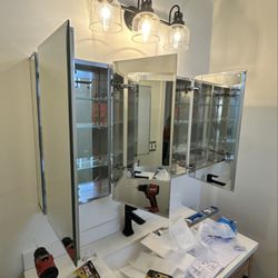 KapMorgan - Bathroom vanity fit-out: double vanity set and levelled, mirrors hung, light bar mounted.