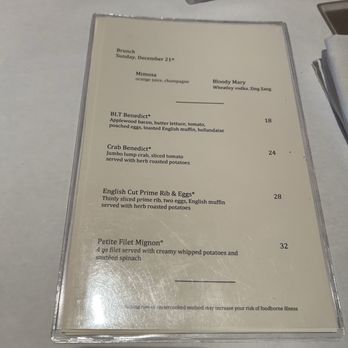 BrickTop's - Menu - A brunch menu from a restaurant, dated Sunday, December 21st, with options including BLT Benedict, Crab Benedict, English Cut Prime Rib & Eggs, and Petite Filet Mignon. The menu details ingredients and prices for each dish, and is placed on a white table with other menus and tableware partially visible. - New American Near Me - Frontenac, Missouri