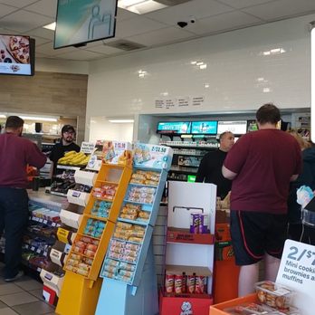 7-Eleven - Checkout counter with cashier and suspected non uniformed worker in black mock neck shirt. - Gas Stations Near Me - Fort Worth, Texas