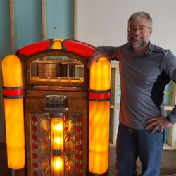 Tin Roof Dairy - Owner Mike Yount poses with his working original model 800 Wurlitzer jukebox, which now occupies a prominent spot in Tin Roof Dairy.