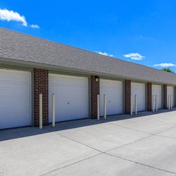 Meadow Ridge Apartments - A row of closed garage doors with a brick wall and a clear blue sky in the background.