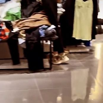 ZARA - The image shows a retail clothing store interior with tables and racks filled with various garments such as jackets, shirts, and pants. Several shoppers are browsing the clothing items, with some seated and others standing. The store has a tiled floor and appears to be well-lit, with clothing organized in different sections. - Women's Clothing Near Me - Troy, Michigan