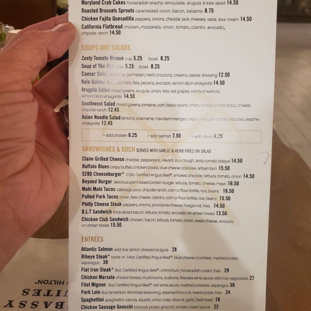 Claim Restaurant & Libations - a hand holding a menu - Bars Near Me - Denver, Colorado