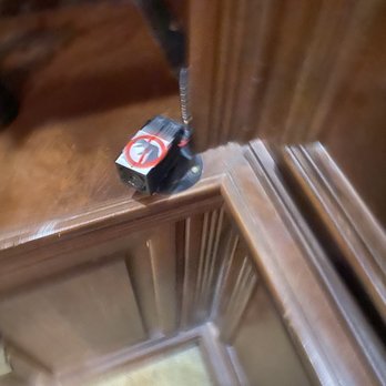 Escape Room 101 - Very Dusty! - Blurry image showing an elevator corner with a wooden panel and a black device on the surface, possibly a security or control device. - Escape Games Near Me - Phoenix, Arizona
