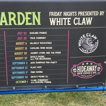 Hideaway Brew Garden - Outdoor event schedule board at Hideaway Brew Garden & Bar displaying dates and names of upcoming events such as dueling pianos, live music, and festivals from July to October. The board features colorful text and logos, including the White Claw logo and the Hideaway Brew Garden & Bar branding. - Beer Gardens Near Me - Hoffman Estates, Illinois