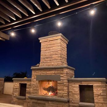 PACD - a patio with a fire place and string lights - Landscaping Near Me PACD - a patio with a fire place and string lights - Landscaping Near Me