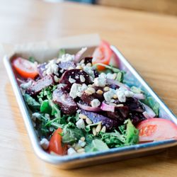 The Cabin Kitchen - Our Beet Tomato Salad is made with roasted beets, tomatoes & onions, tossed in a citrus-hefeweizen vinaigrette, served on a bed of greens