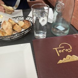 Seated in patio with menus, bread, and bottle of water