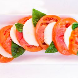 Pino - Caprese Salad: fresh mozzarella layered with vibrant heirloom tomatoes, basil leaves, and a drizzle of extra virgin olive oil and balsamic