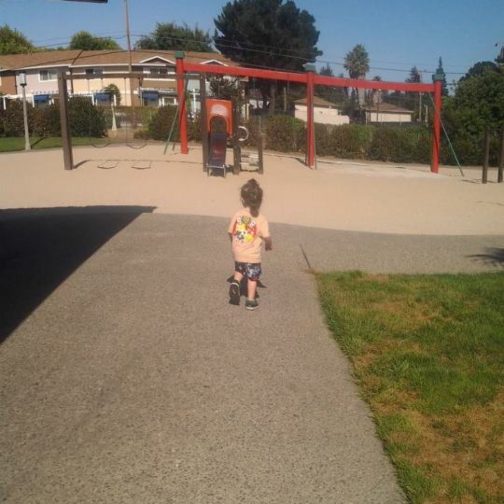 Braly Park - one of the park structures surrounded in sand, swings in background. - Parks Near Me - Sunnyvale, California
