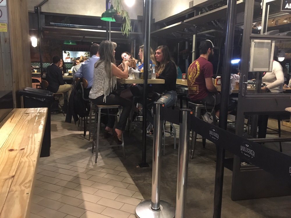 Bullguer Perdizes - "Mesas" (três balcões finos e compridos onde se sentam de ambos os lados) no salão interno - outside - Burgers Near Me - São Paulo, SP Bullguer Perdizes - "Mesas" (três balcões finos e compridos onde se sentam de ambos os lados) no salão interno - outside - Burgers Near Me - São Paulo, SP
