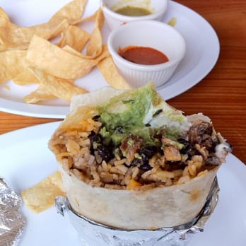 La Mission - Pollo asado burrito with chips in the background - Mexican Near Me - Berkeley, California La Mission - Pollo asado burrito with chips in the background - Mexican Near Me - Berkeley, California