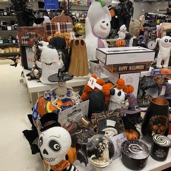 Marshalls - A retail store display features Halloween-themed decorations such as skeletons, pumpkins, skulls, and ghost figurines. The decorations include a skeleton with a witch hat, a skull with a top hat, a snow globe with a bride and groom, and various pumpkin and ghost ornaments. The background shows shelves with additional products and store fixtures, indicating a seasonal display for Halloween shopping. - Department Stores Near Me - Fairfield, Connecticut