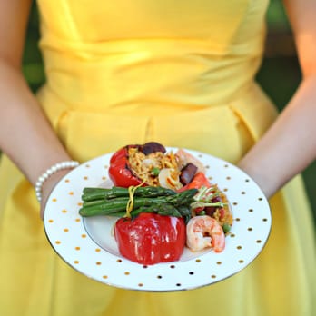 Catering Capers - a woman in a yellow dress holding a plate of food - Party & Event Planning Near Me - Tallahassee, Florida