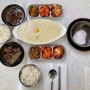 Photo of Mountain Cafe - Los Angeles, CA, United States. Abalone porridge with egg, jangjorim (soy braised beef), pickled radish, radish kimchi, and cabbage kimchi. Dipping salt is for gamgyetang.