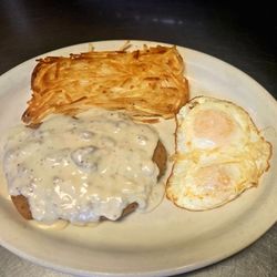 Bobby's Café - Golden-battered chicken fried steak, smothered in homemade country gravy, served with over medium eggs, & crispy hashbrowns.