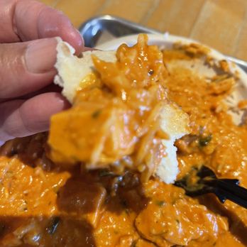 Masala Wok Indian + Asian Fare - a hand holding a piece of bread - Indian Near Me - Katy, Texas Masala Wok Indian + Asian Fare - a hand holding a piece of bread - Indian Near Me - Katy, Texas