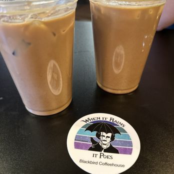 Blackbird Coffee House - Blackbird Coffee - Two iced coffee beverages in clear plastic cups are placed on a black table, with a Blackbird Coffeehouse coaster nearby. - Coffee & Tea Near Me - Albuquerque, New Mexico