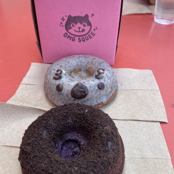 Omg Squee - Sesame donut in the back (with the cute face) and the Ube Oreo in the front - Desserts Near Me - Austin, Texas Omg Squee - Sesame donut in the back (with the cute face) and the Ube Oreo in the front - Desserts Near Me - Austin, Texas
