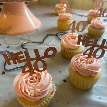 Molly's Bakery - Vanilla cupcakes with raspberry filling - Cupcakes with pink frosting and 'HELLO 40' toppers are arranged on a decorated table for a celebration. - Bakeries Near Me - Beacon Falls, Connecticut
