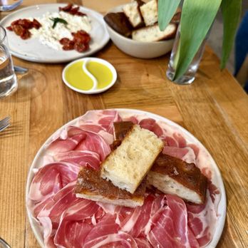 Roscioli - Prosciutto and focaccia in front, burrata with semi-dried tomatoes in the back - Italian Near Me - New York, New York Roscioli - Prosciutto and focaccia in front, burrata with semi-dried tomatoes in the back - Italian Near Me - New York, New York