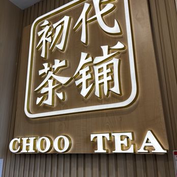 Choo Tea - Logo - The image shows an illuminated sign with Chinese characters and the words "CHOO TEA" in bold, capitalized letters. The sign is mounted on a wooden wall with vertical paneling, suggesting an interior setting of a tea shop or cafe. The lighting highlights the characters and text, creating a modern and inviting atmosphere. - Bubble Tea Near Me - Toronto, Ontario